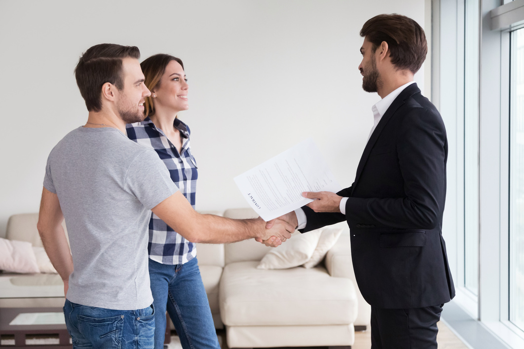 Real Estate Agent or landlord handshaking couple tenants make real estate deal